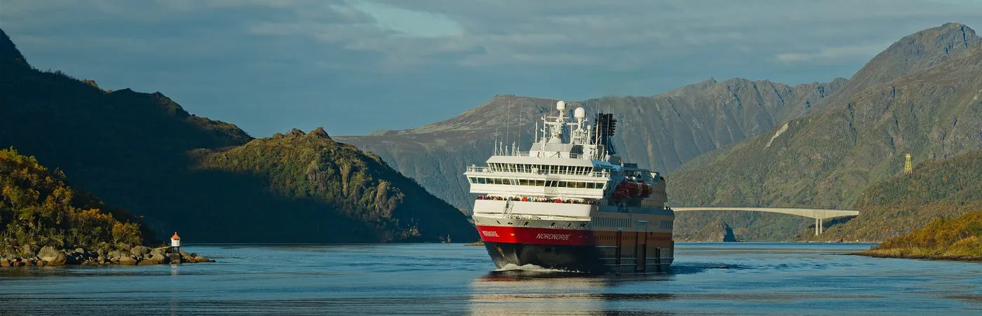 Hurtigruten coastal ship sailing between northern Norwegian mountains